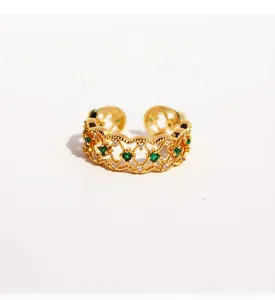 Detail of vintage emerald zircon ring with hollow lace pattern and gold plating