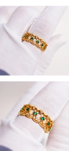 Macro detail of vintage gold lace hollow ring with emerald green zircon accents