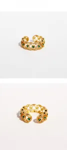 Detail of vintage gold ring with green zircon and hollow lace patterns on white background