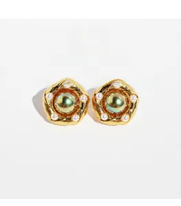 Detail of vintage gold-plated brass earrings featuring large green iridescent pearls