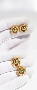 Detailed macro view of vintage brass gold-plated earrings with green pearls and spiral design