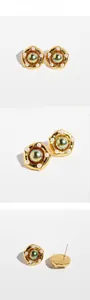 Macro view of French vintage gold-plated swirl earrings with pearl and green stone