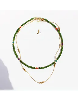 Detail of double-layered necklace featuring green faceted beads and gold plated brass chain