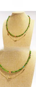 Detail of double-layer necklace with green faceted beads and fine gold chain layering