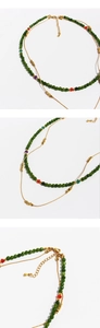 Detail of double-layered necklace with green faceted beads and golden cube pendants