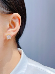 Gros plan d'une boucle d'oreille carrée en zircon avec bordure perlée dorée