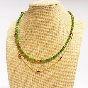 Double-layered beaded necklace with green faceted stones and gold chain accents