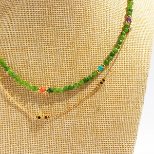 Double-layered necklace with faceted green beads and minimalist gold chain on a neck model