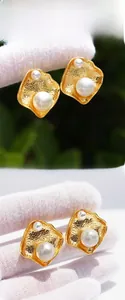 Dettaglio di orecchini irregolari placcati oro con doppie perle e finitura martellata