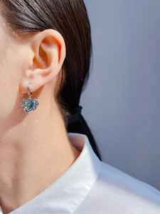 Close-up of heart-shaped sea blue zircon earrings with liquid lava silver metal frame