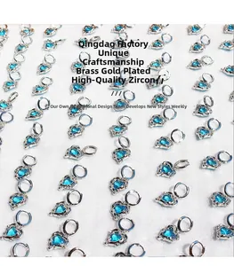 Flat lay of multiple silver heart earrings with blue cubic zirconia stones on white foam