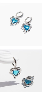 Macro shot of liquid metal heart earrings featuring deep blue heart-shaped crystals