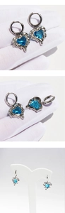 Macro detail of liquid silver lava heart earrings with faceted ocean blue zircon stones