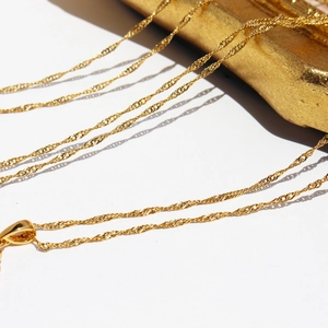 Collier chaîne dorée à maille torsadée effet vagues sur fond blanc élégant et raffiné