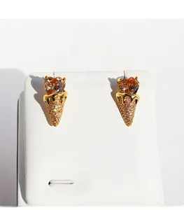 Macro view of gold-plated ice cream stud earrings with heart-shaped amber zircon stones