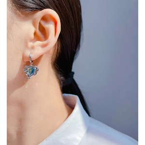 Elegant silver huggie earrings with heart-shaped ocean blue zircon on female model