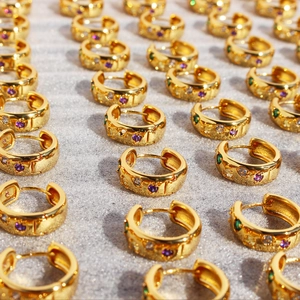 Créoles dorées avec zircons colorés et motifs d'étoiles présentées en un motif ordonné
