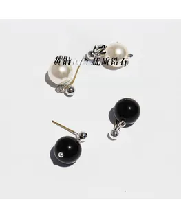 Detailed view of gold plated brass earrings featuring white pearls and black agate beads