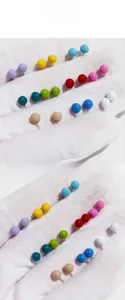 Macro shot of colorful enamel bead stud earrings in yellow pink blue and white