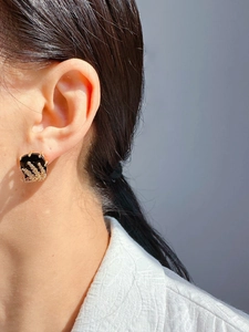Detailed close-up of a vintage black gemstone earring with gold wheat ear carving