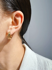 Detailed view of gold twisted hoop earrings showing vintage texture on a model