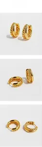 Detail view of gold-plated brass hoop earrings with double-layered twist and smooth textures