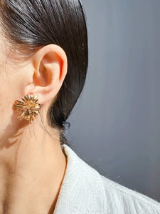 Detailed view of vintage gold sunflower stud earring with zircon center worn by model