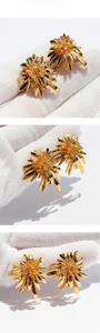 Macro detail of gold flower earrings with sparkling zircon centers on white background