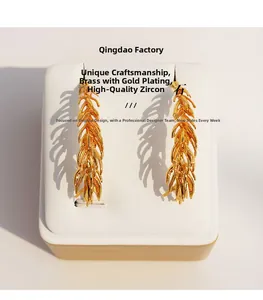 Detail of gold-plated brass feather earrings with layered wheat leaf design and zircons