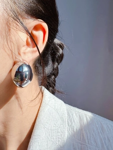 Close-up of model wearing large oversized silver mirror finish spherical stud earrings