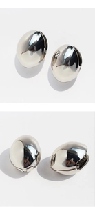 Detailed close-up of chunky silver hollow oval earrings with a high-shine mirror finish