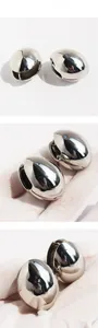 Detailed views of polished silver oval hollow earrings with secure snap closure mechanism