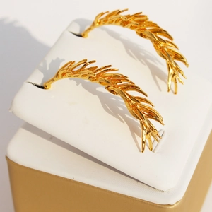 Elegant gold leaf tassel earrings with wheat spike design on a white jewelry stand