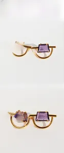 Detailed view of geometric gold earrings with purple step-cut zircon in natural light