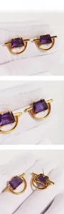 Detail shot of gold geometric earrings featuring square purple zircon stone settings