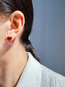 Close-up of double layered red and pink heart zircon earrings worn by a model