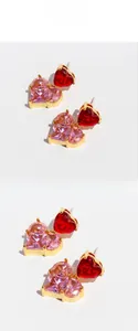 Macro detail of heart-shaped zircon earrings with pink and red gems in gold setting