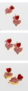Macro detail of heart-shaped pink and red zircon earrings with gold plating finish