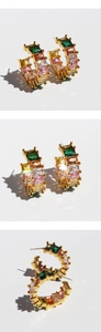Detailed macro view of C-shaped gold hoop earrings with multi-color rectangular zirconias