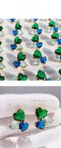 Detailed view of cluster heart earrings featuring blue and green zircon stones in gold claws