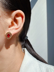 Close-up of vintage oval red zircon earring with gold plating and pavé accents