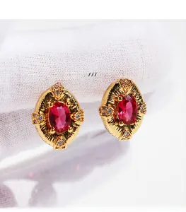 Macro detail of oval red zircon earrings with 18K gold plating and vintage royal textures