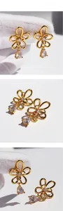 Macro detail of gold flower earrings with drop-shaped zircon pendants on white background