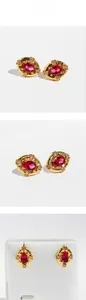 Detail of vintage gold oval stud earrings with large red zircon and small white diamonds