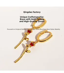 Detail of red enamel rose earrings in gold plated brass with zircon inlay