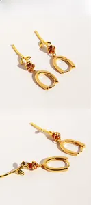 Detailed macro view of red enamel rose earrings with gold-plated U-shaped ear buckles