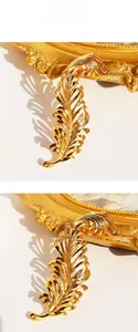 Detailed close-up of a 3D golden feather brooch with hollow metal texture and polished finish