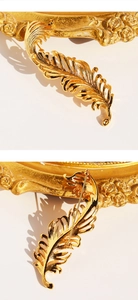 Detailed view of golden 3D feather brooch showing intricate brushed texture and back clasp