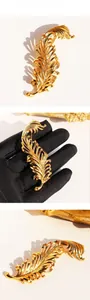 Detail view of gold-plated feather brooch showing intricate hollow engraving and texture