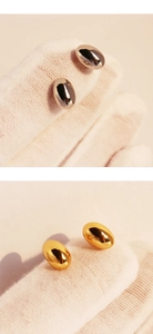 Polished gold and silver oval stud earrings shown on jewelry glove for detail